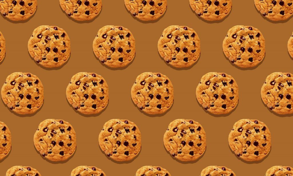 A pattern of chocolate chip cookies on a brown background.