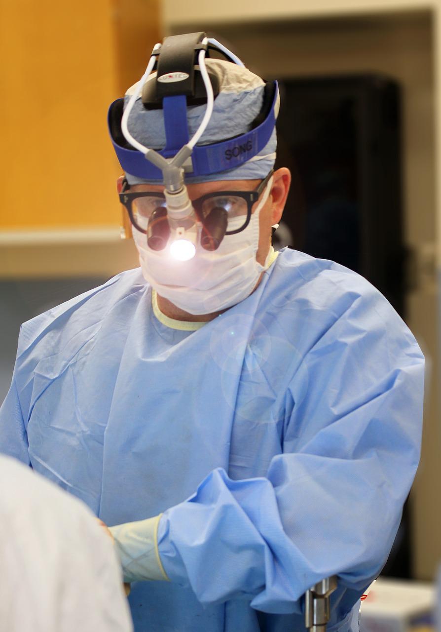 An image of a doctor in an operating room wearing scrubs and face shield.